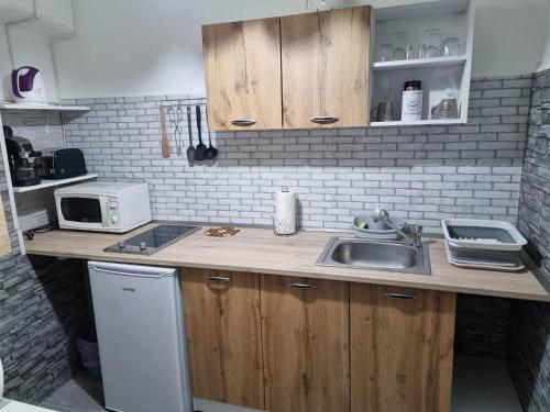 a kitchen with a sink and a microwave at Napfény Apartman in Bogács