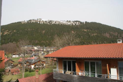a house with a red roof with a mountain in the background at Ferienwohnung Bachmann in Oberjoch