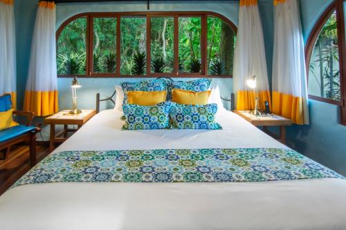 a bedroom with a white bed with blue and yellow pillows at Finca Rosa Blanca Coffee Farm and Inn in Heredia