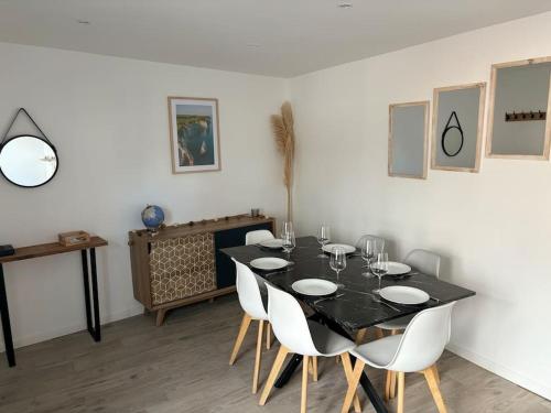 une salle à manger avec une table noire et des chaises blanches dans l'établissement Maison de ville proche baie de Somme, à Abbeville