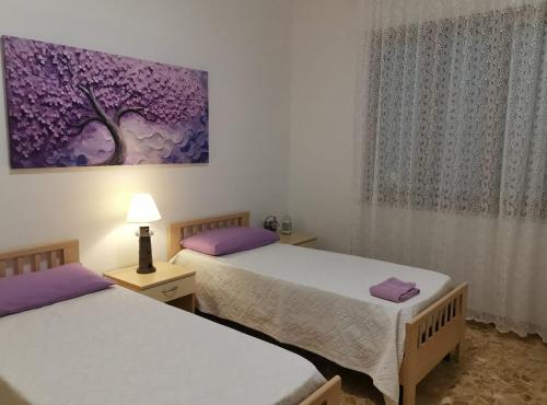 a bedroom with two beds and a painting on the wall at App.Violet Sardegna Mare La Caletta in La Caletta