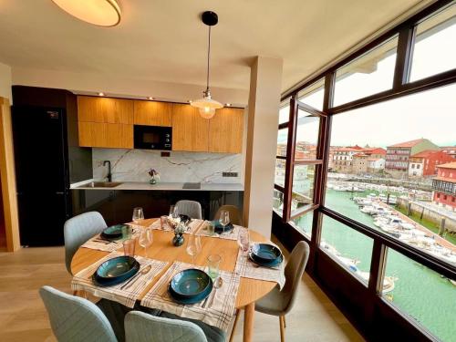 a dining room with a table with chairs and a large window at Apartamento El Mirador del Puerto in Llanes