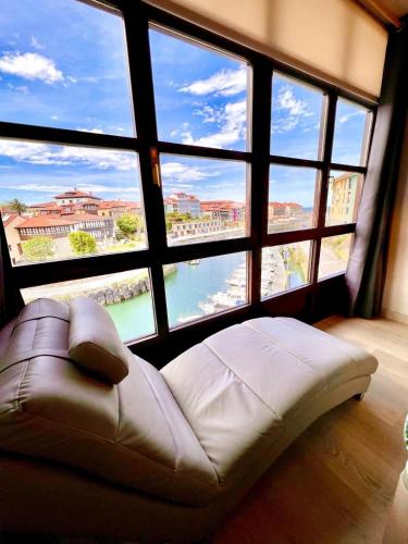 a large room with a couch in front of a large window at Apartamento El Mirador del Puerto in Llanes