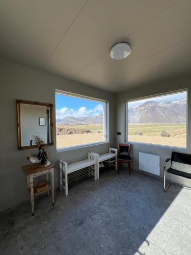 a room with two windows and a table and chairs at Sauðanes Guesthouse in Höfn