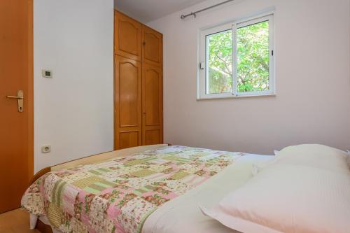 a white bedroom with a bed and a window at Apartments Agneza Tucepi in Tučepi