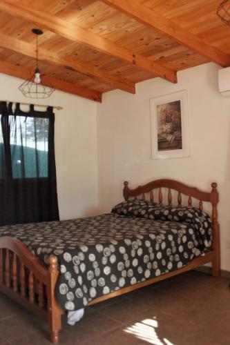 a bedroom with a wooden bed in a room at Cabañas LA BUENA FE in La Falda