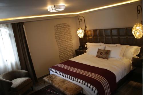 a bedroom with a large bed and a chair at Casa 1810 Hotel Boutique in San Miguel de Allende