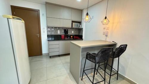 a kitchen with a counter and two stools in it at Monte Carmel in Ribeirão Preto