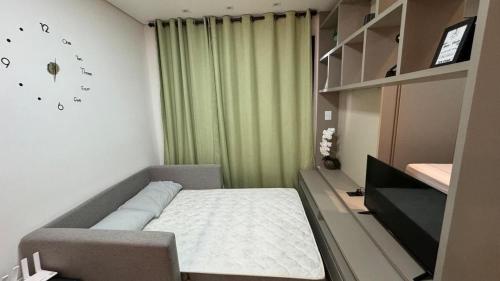 a small bedroom with a bed and a green curtain at Monte Carmel in Ribeirão Preto