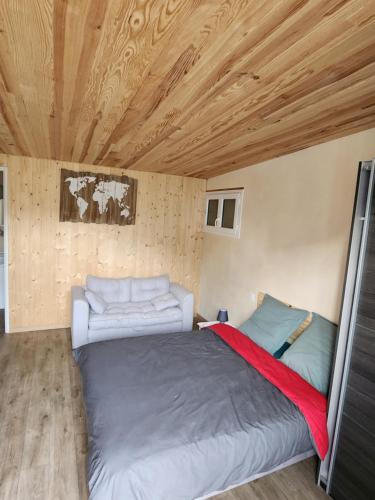 a bed and a couch in a room with wooden ceilings at Au Balaway in Louey