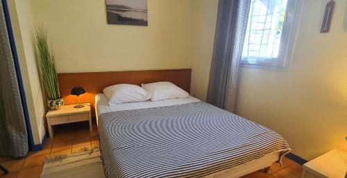 a small bed in a room with a window at Cottage du Golf en Morbihan in Ploemel