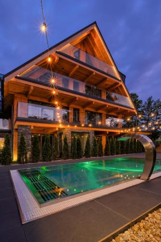 a house with a swimming pool in front of it at Białka SPA & Resort, Odkryj-Białkę in Białka Tatrzańska