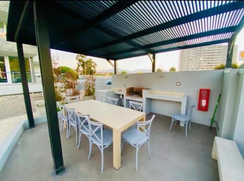 a patio with a table and chairs under a roof at Departamento Playa La Herradura in Coquimbo