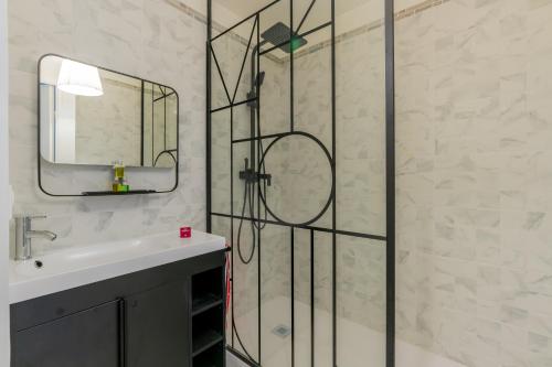 une salle de bain avec une douche avec un lavabo et un miroir dans l'établissement Le Borely, côté Marina Olympique, à Marseille