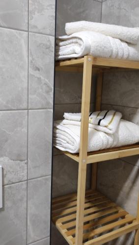 プリトヴィッツェ湖群にあるStudio apartman Roseのバスルームの木製棚にタオルを積み重ねます。