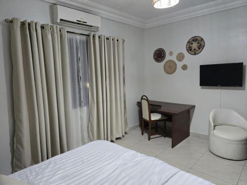 科托努Acropole Hotel的一间卧室，配有一张床、一张书桌和一台电视
