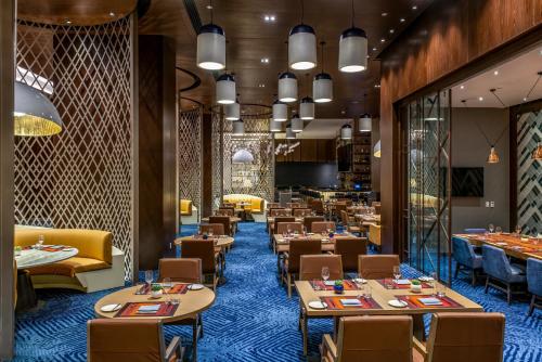 a dining room with tables and chairs and a restaurant at Hilton Guadalajara Midtown in Guadalajara