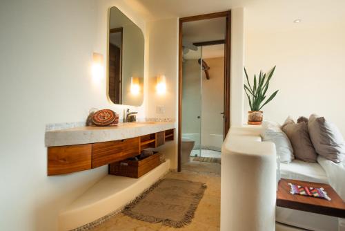 a bathroom with a sink and a mirror and a couch at Armadillo Living Villas in Zihuatanejo