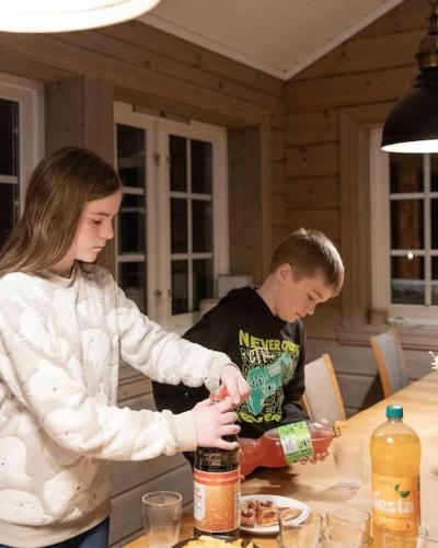 a boy and a girl standing at a table preparing food at Family Lodge in Stryn in Stryn