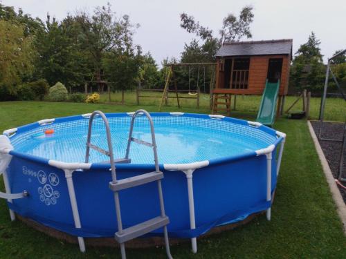 une grande baignoire bleue dans une cour avec une aire de jeux dans l'établissement Maison 15 min du Mont St Michel, à Saint-James