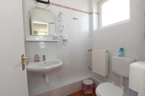a white bathroom with a sink and a toilet at Villa Nova in Hévíz