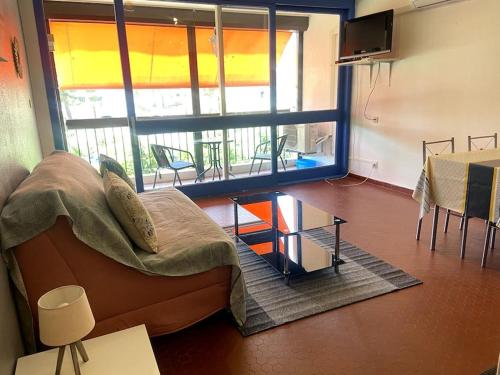 un salon avec un canapé et une grande fenêtre dans l'établissement Studio à 2 pas du port, à Saint-Cyprien