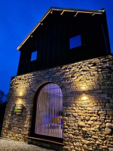 - un bâtiment en pierre avec une fenêtre éclairée dans l'établissement Lunic1926, à Manhay