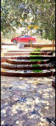 a red car parked next to a set of stairs at مزرعة وشاليه السلطانة مرج الحمام in Al Baḩḩāth