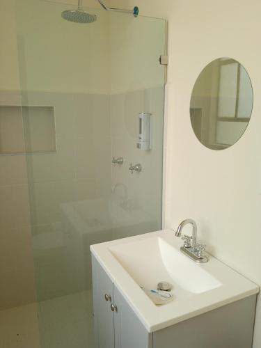 a white bathroom with a sink and a shower at Casa IAIA in Mexico City
