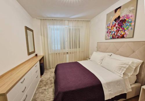 a bedroom with a large bed and a window at Apartman Diana in Zadar