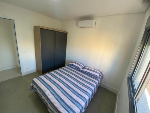 a small bedroom with a striped bed in a room at Guaruja Terrazza Ap de Alto Padrão Enseada in Guarujá