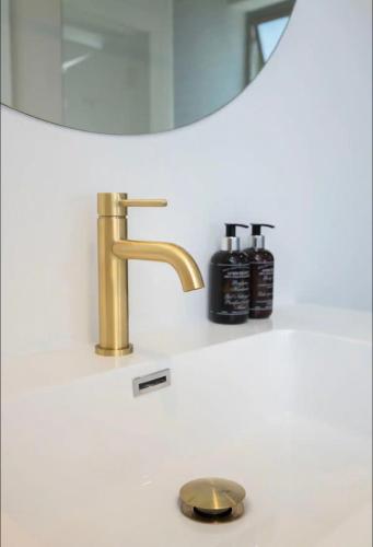 a bathroom sink with a gold faucet and a mirror at Stunning House in Constantia in Cape Town