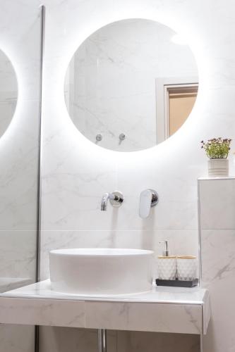 a white bathroom with a sink and a mirror at Paralia Luxury Apartment in Paralia Katerinis
