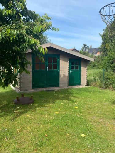 a house with green doors and a cat in the yard at Oase der Ruhe 2 in Waldsieversdorf