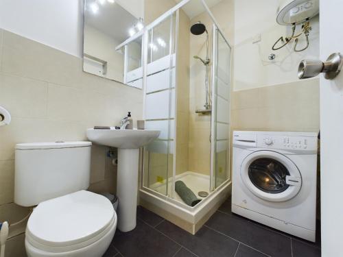 a bathroom with a toilet and a sink and a washing machine at Hidden Gem Hideaway Retreat in Central Town Area with AC in Gibraltar