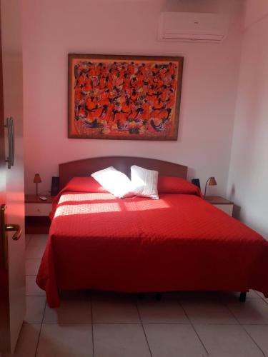 a bedroom with a red bed with a painting on the wall at FronteMare in San Cataldo