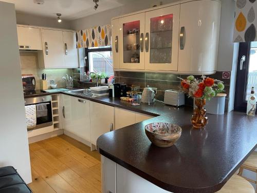 a kitchen with white cabinets and a black counter top at 5 The Galleries in Spean Bridge