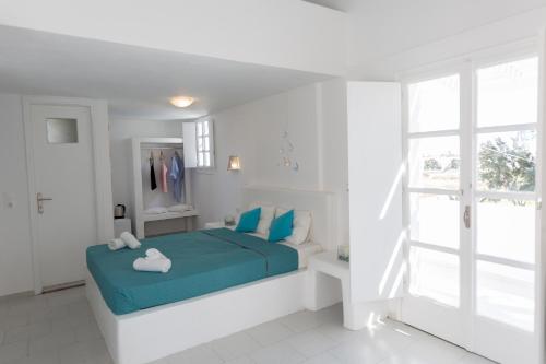 a white bedroom with a blue bed and a window at Sfiga villas in Perissa