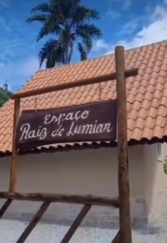 a sign in front of a building with a palm tree at Chalé Espaço Raiz de Lumiar in Nova Friburgo