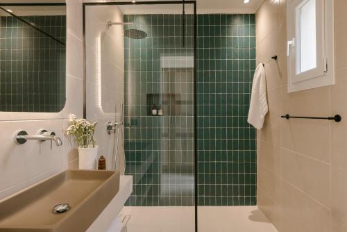 a green tiled bathroom with a shower and a sink at Rodi Studios in Karavadhos