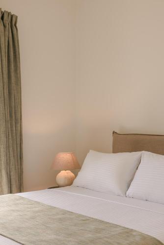 a bed with white sheets and a lamp at Rodi Studios in Karavadhos