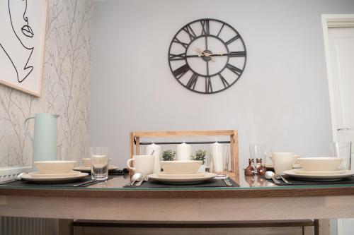 a table with plates and a clock on the wall at Comfy Modern 3BR Semi Detached 400Mb Wifi Free Double Parking in Kenton