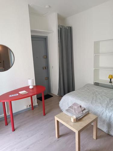 - une chambre avec une table rouge et un lit dans l'établissement Studio avec balcon, à Pau