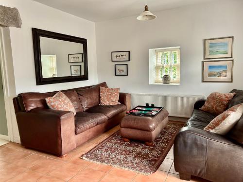 a living room with a leather couch and a table at The Gables Cottage in Rathvilly