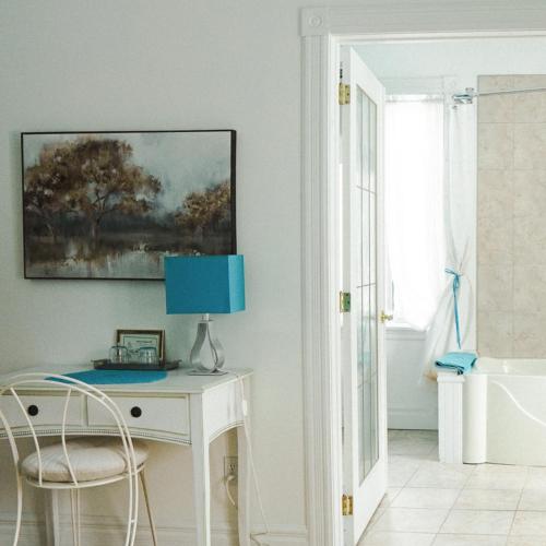 a white desk with a blue lamp and a window at Auberge Incroyable in Saint Adrien