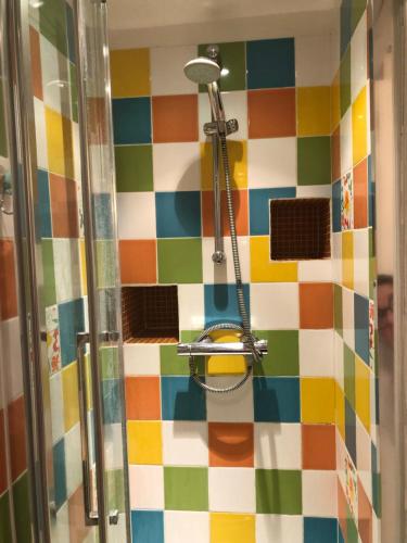 La salle de bains est pourvue d'une douche et de carrelage coloré. dans l'établissement Splendide Loft Central - JO 2024 - Stade de France, à Saint-Denis