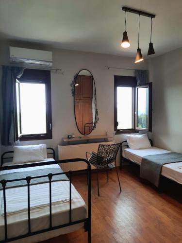 a room with two beds and a chair and a mirror at House with View in Agia Paraskevi
