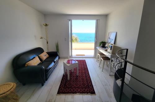 un salon avec un canapé en cuir noir et une table dans l'établissement Le Cabanon, pieds dans l'eau, vue exceptionnelle, à Fréjus