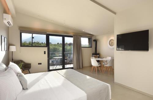 a bedroom with a bed and a television and a table at Olive All-Seasons Suites, Panel Hospitality Homes & Villas in Litochoro