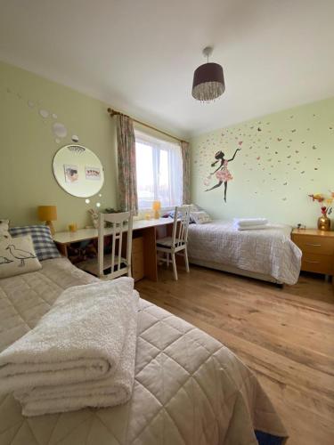 a bedroom with two beds and a desk and a table at Stunning 3 bedroom house with 2 bathrooms in Mansewood